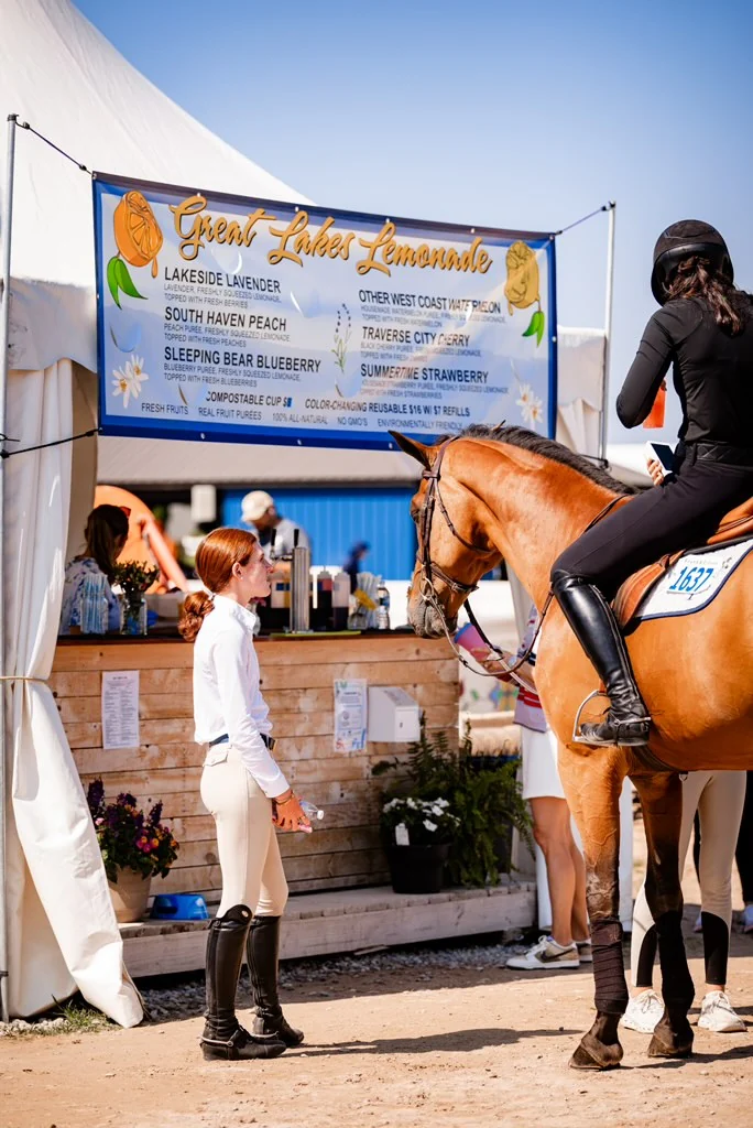 Riders and a horse beside the Great Lakes Lemonade booth