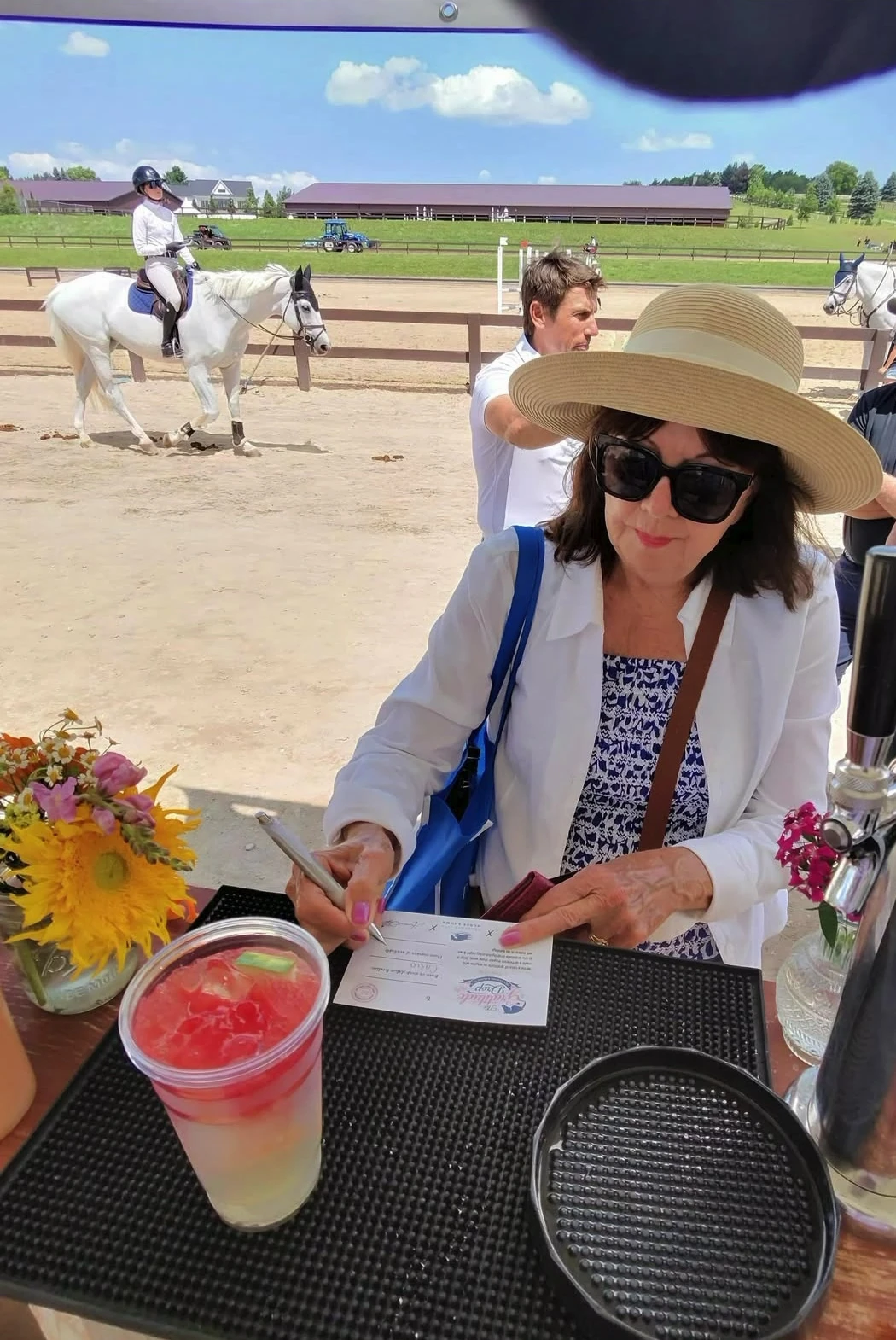 Lemonade service at an equestrian venue with a colorful drink and riders in the background