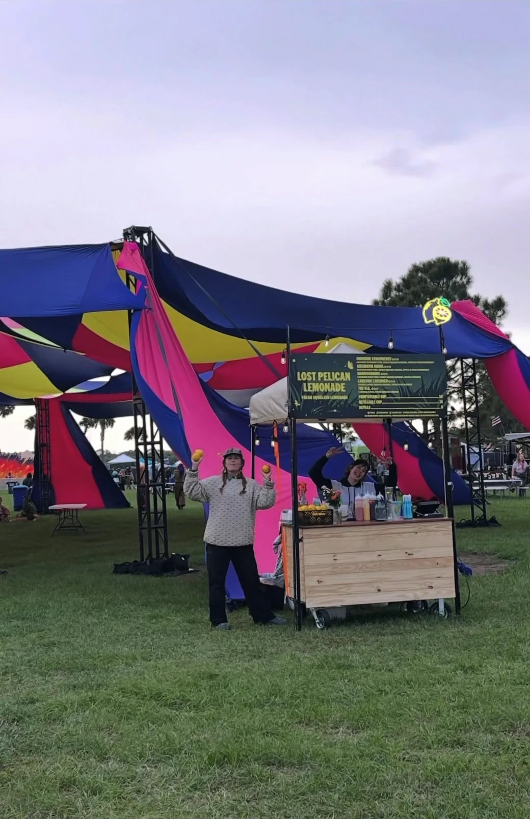 Lost Pelican Lemonade's cart in front of a colorful festival tent with people beside it