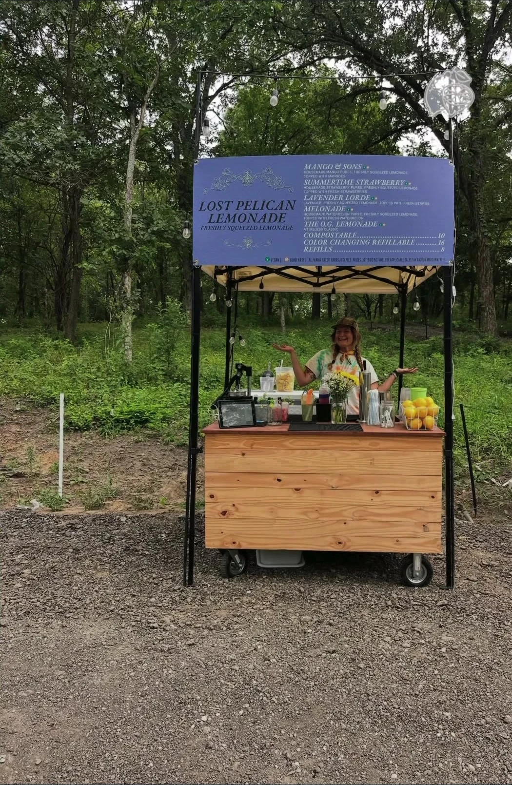 Lost Pelican Lemonade's wooden booth, menu, fresh lemons, and a team member among trees